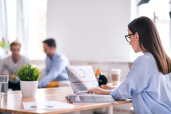 Angenehme konzentrierte Frau sitzt am Tisch — Stockfoto