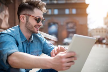 Ayak üzerinde oturan memnun gülümseyen adam