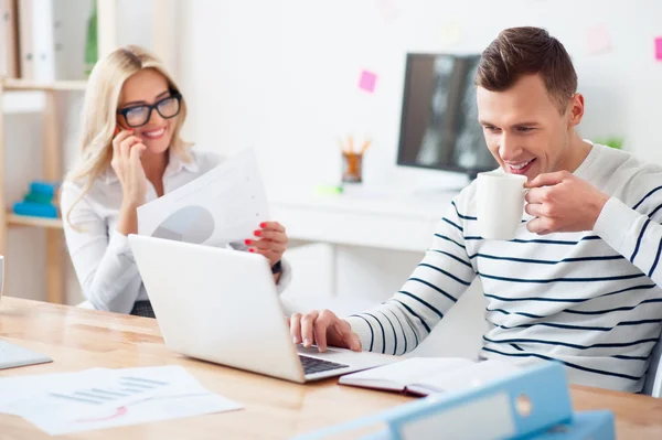 Ragazzo positivo che beve caffè al lavoro — Foto Stock