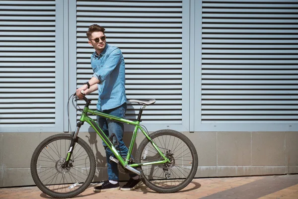 Agradable chico sosteniendo su bicicleta — Foto de Stock