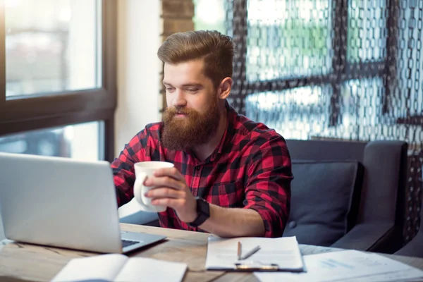 Vrolijke bebaarde man zittend aan tafel — Stockfoto