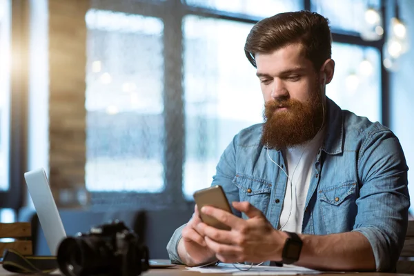 Приємний бородатий чоловік сидить за столом — стокове фото