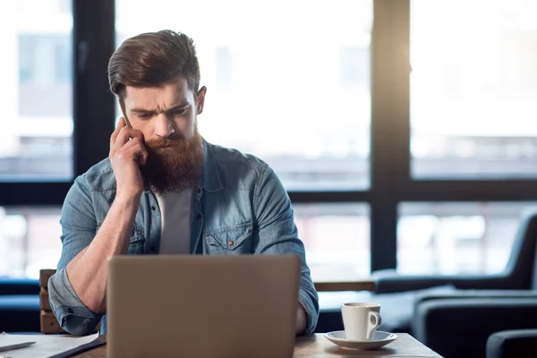 Angenehmer bärtiger Mann sitzt am Tisch — Stockfoto