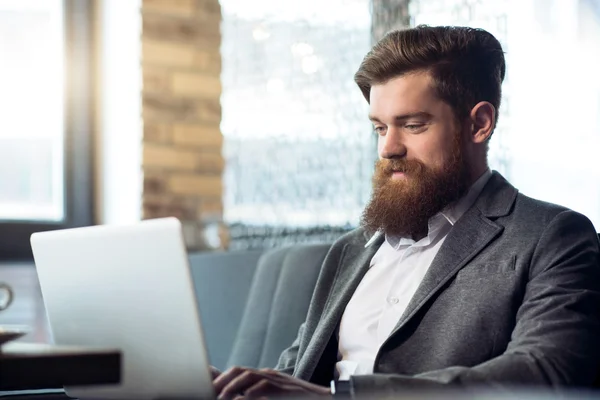 Blij bebaarde man werken aan de laptop — Stockfoto