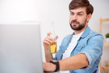 Dizüstü bilgisayarda çalışan ve içecek içme adam