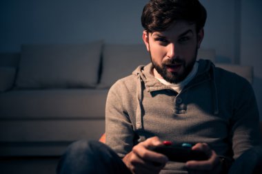 Bir video oyunu denetleyicisi elinde tutan adam