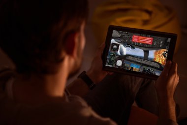 Bir tablet tutarak ve video oyunu oynayan adam