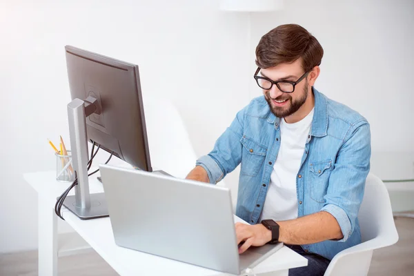 Šťastný mladý muž pracuje na jeho laptopu — Stock fotografie