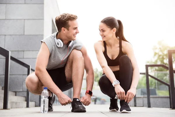 Pareja en cuclillas y atándose los cordones — Foto de Stock