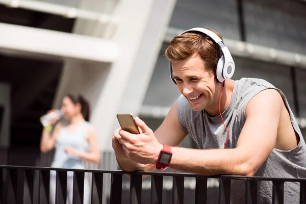 Homem sorrindo e usando fone de ouvido após o treinamento — Fotografia de Stock