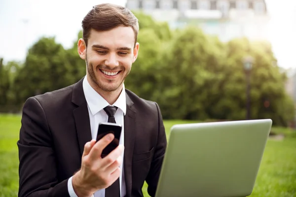 Knappe blij man zittend op het gras — Stockfoto