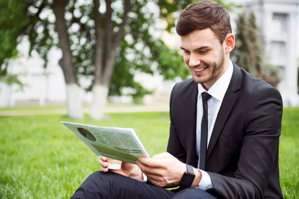 Homme souriant positif assis sur l'herbe — Photo