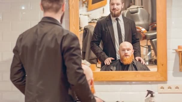 Веселий перукар спілкується зі своїм клієнтом — стокове відео