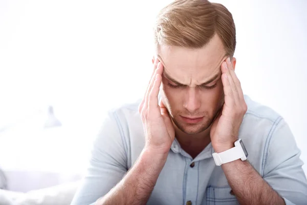 Moody sick man sitting on the settee — Stock Photo, Image