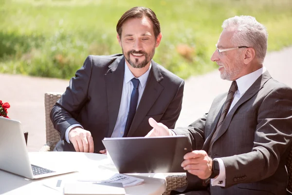 Compañeros sonrientes y alegres sentados a la mesa — Foto de Stock