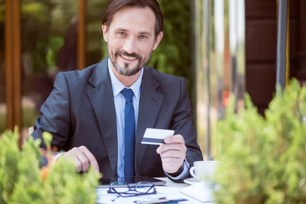 Guapo hombre sonriente sentado a la mesa —  Fotos de Stock