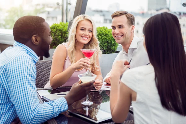 Vrolijk lachende vrienden zitten in het cafe — Stockfoto