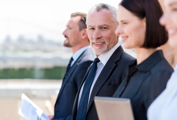 Vrolijke man staat met zijn collega's — Stockfoto