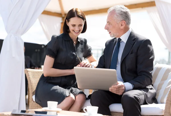 Aangename lachende collega's zitten aan de tafel — Stockfoto