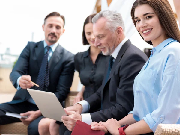 Mujer sonriente positiva sentada con sus colegas — Foto de Stock