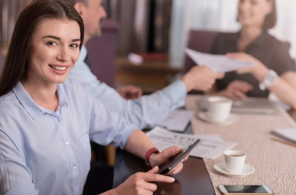 Positive schöne Frau sitzt am Tisch — Stockfoto