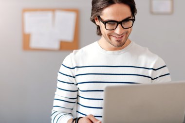 Dizüstü bilgisayar kullanan neşeli yakışıklı adam