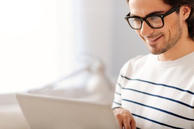 Joyful yakışıklı adam dizüstü bilgisayar kullanarak