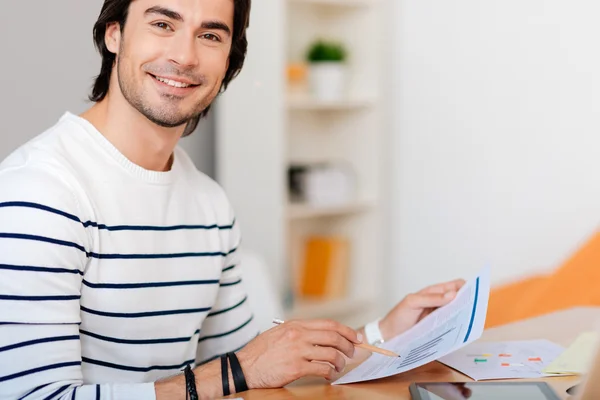 Bonito homem alegre sentado à mesa — Fotografia de Stock