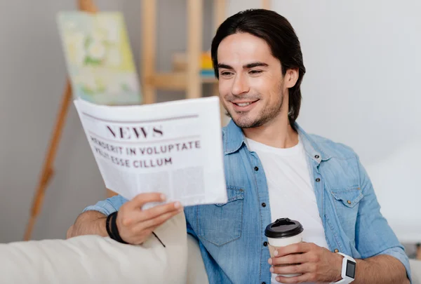 Trevlig leende man läser tidningen — Stockfoto