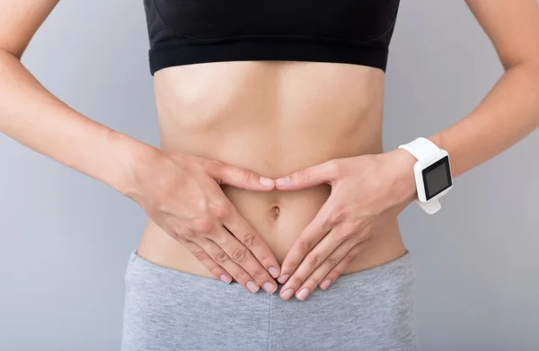 Mujer agradable manteniendo las manos en su vientre — Foto de Stock