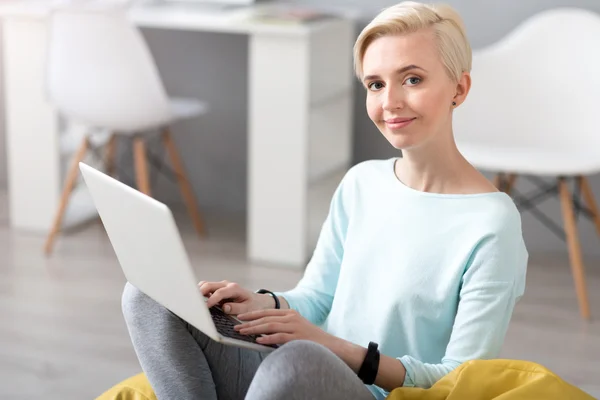 Woman looking at camera and using laptop — Stock Photo, Image