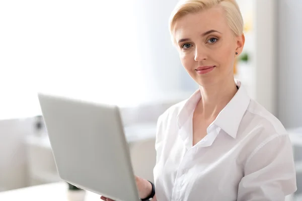 Vrouw kijken naar camera ingedrukt te laptop — Stockfoto