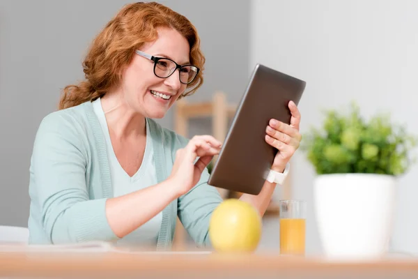 Duygusal neşeli kadın oturma kullanarak tablet — Stok fotoğraf