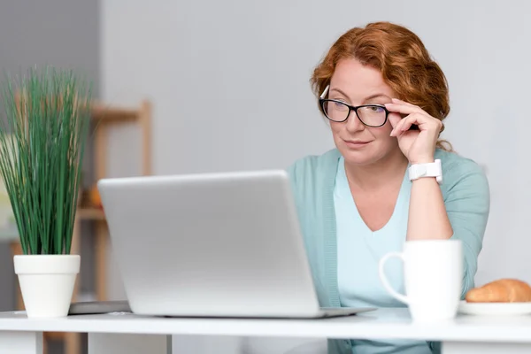 Angenehme konzentrierte Frau sitzt am Tisch — Stockfoto