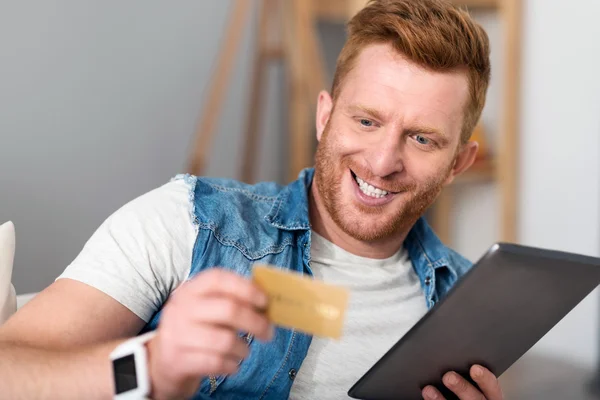 Homem bonito alegre segurando cartão de crédito — Fotografia de Stock