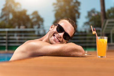 Yüzme havuzunda dinlenen pozitif gülümseyen adam