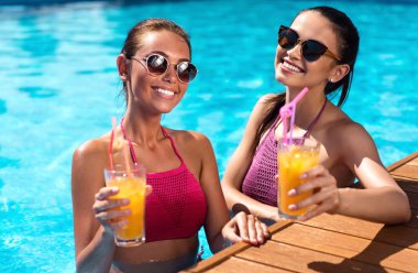 Bir yüzme havuzunda dinlenen neşeli arkadaşlar