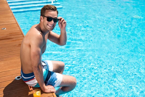 Positiv aufgenommener Mann sitzt in Schwimmbadnähe — Stockfoto