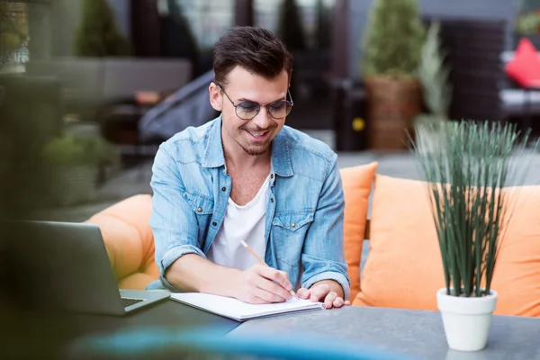 Fröhlicher Mann macht sich Notizen — Stockfoto