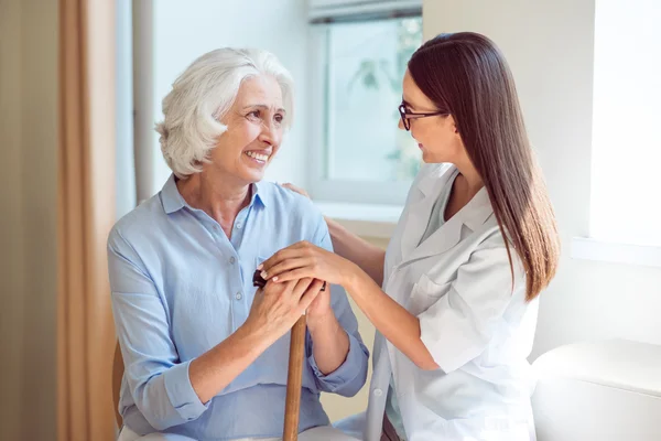 Jonge verpleegster omhelst senior vrouw — Stockfoto