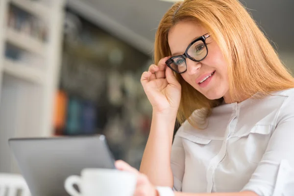 Mujer sonriente agradable sentada a la mesa —  Fotos de Stock