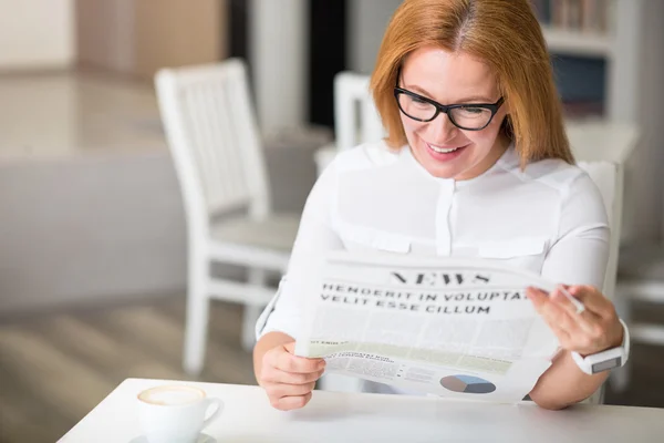 Радостная женщина читает газету — стоковое фото