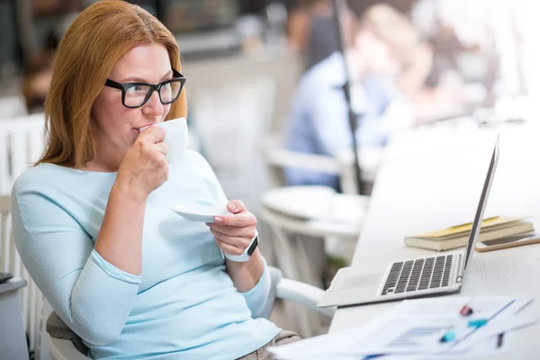 Trevlig innehåll kvinna sitter vid bordet — Stockfoto