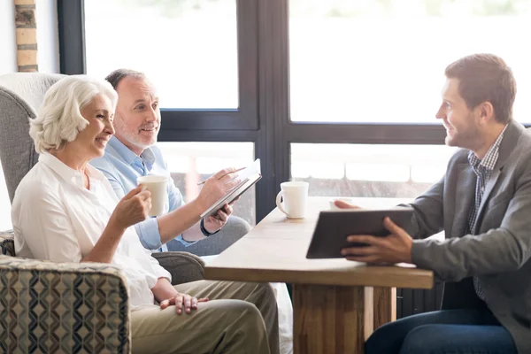 Fröhlicher Verkaufsleiter im Gespräch mit Senioren-Paar — Stockfoto