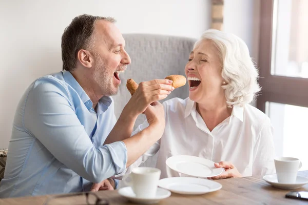 Joyeux couple de personnes âgées mangeant croissant — Photo