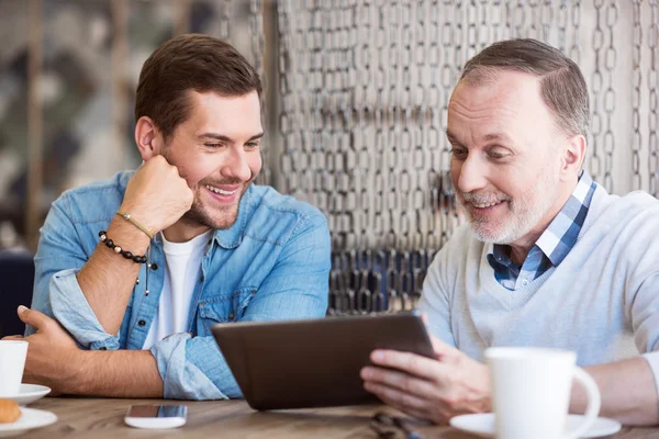 Homme positif et son petit-fils adulte utilisant une tablette — Photo