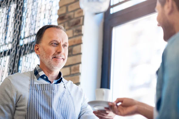 一杯のコーヒーを保持している肯定的な年配の男性 — ストック写真