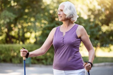 Mutlu emekli kadın güneşli bir gün boyunca yürüyüş yapıyor