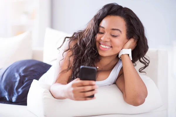 Positivo giovane donna sdraiata sul divano — Foto Stock