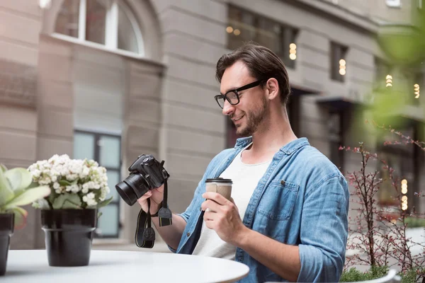 Atraktivní mužský fotograf, který se dívá na fotografie — Stock fotografie